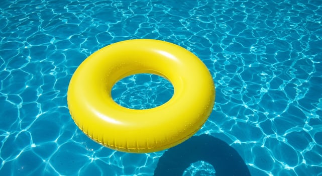 A yellow inflatable ring floating in a pool photo