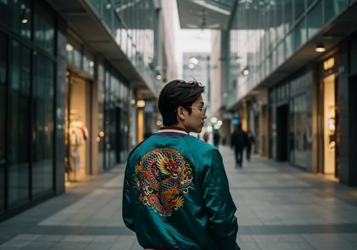 Young man walks through the city, wearing a jacket with dragon emblem on back photo