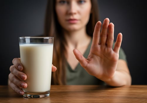 A woman holding a glass of milk and making a stop sign photo