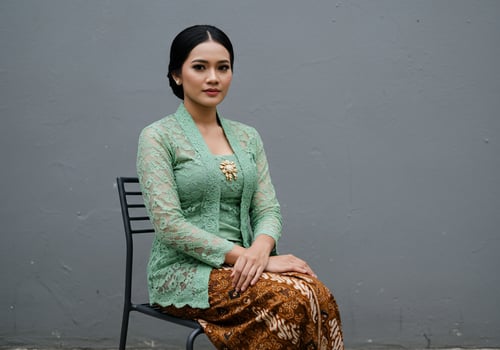 Asian woman wearing kebaya, batik sarong, sits. Tradition, culture, fashion use photo