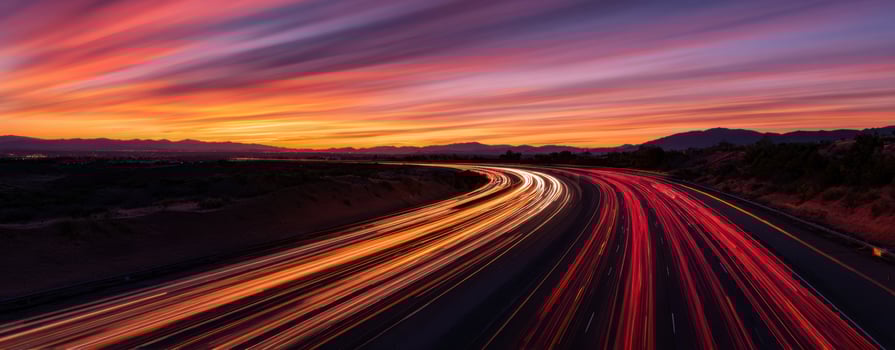 The vibrant highway illuminated by colorful light trails at sunset photo