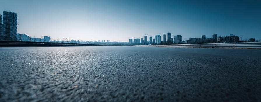The wide asphalt road leading towards a tranquil urban skyline at dawn. photo
