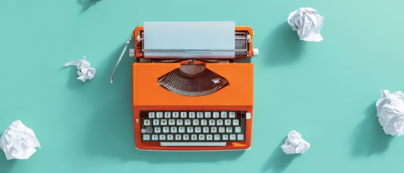 The vibrant orange typewriter surrounded by crumpled papers on teal background. photo
