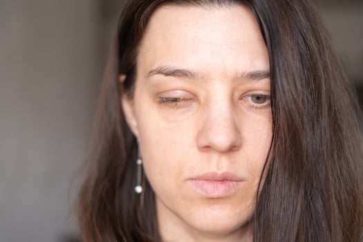 Woman with serious expression and long hair in soft lighting, conveying a moment of reflection in an indoor setting photo