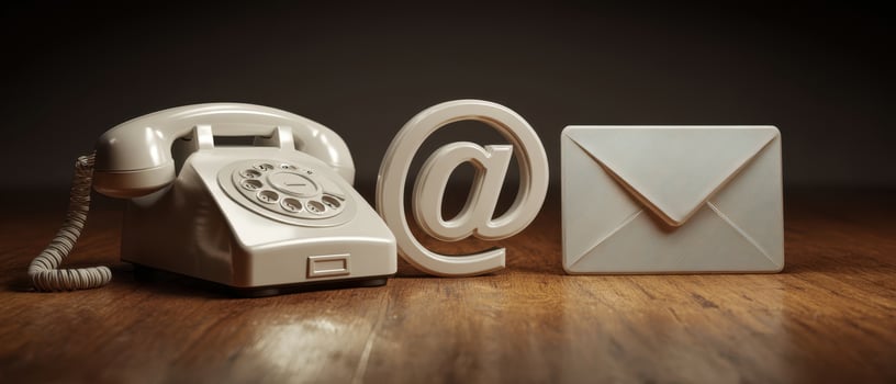 The classic telephone, email symbol, and communication elements on a wooden desk. photo