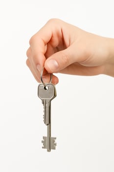 Minimal top view of a human hand holding a metal key against a plain white background. Concept image for real estate, renting, home security, property ownership, or access. photo