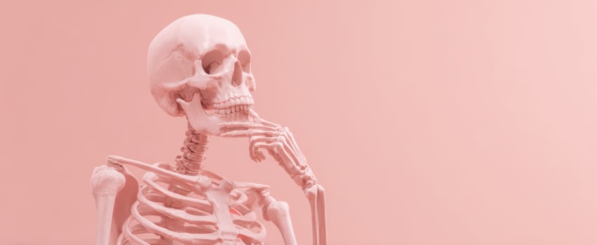 The contemplative skeleton pondering ideas against a pastel pink background. photo