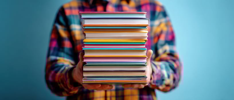 The vibrant stack of books held by a person wearing plaid attire photo