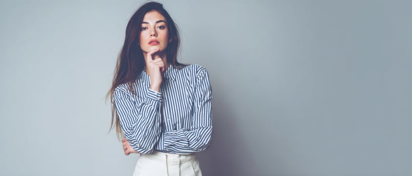 The confident model in a striped shirt with a thoughtful expression against a neutral backdrop. photo