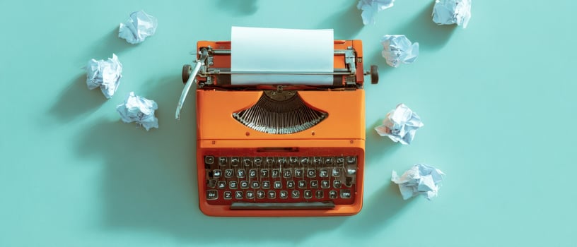 The vintage typewriter surrounded by crumpled paper balls on a teal backdrop. photo