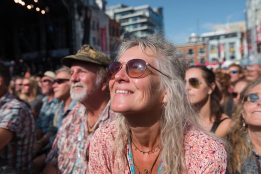 A woman with sunglasses and a hat sitting in the crowd photo