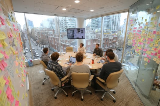 A group of people sitting around a table in an office photo