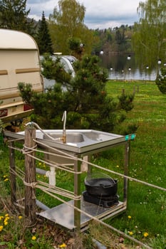 Outdoor stainless steel sink with faucet and kitchen utensils at lakeside camping site photo