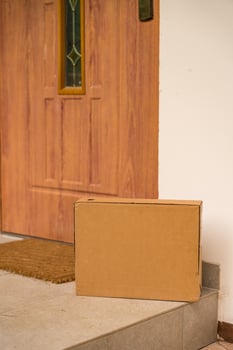 Close-up cardboard box left at the entrance of a wooden country house on a summer day photo