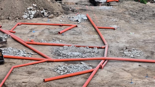 A complex and intricate layout of red pipes can be found on a busy construction site, surrounded by gravel photo