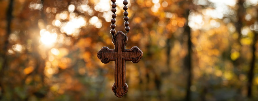 The wooden cross necklace hanging against a vibrant autumn backdrop photo