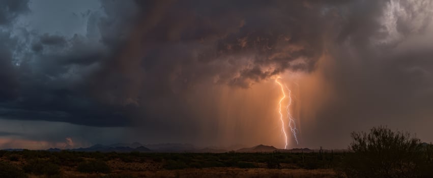 The dramatic lightning striking through a stormy desert sky at dusk. photo