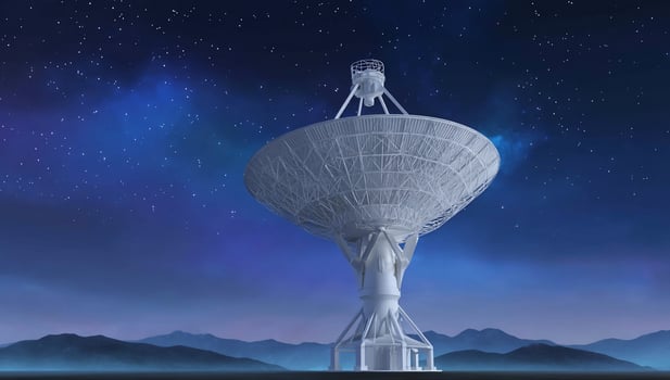 A large satellite dish against a night sky with stars, with mountain backdrop photo
