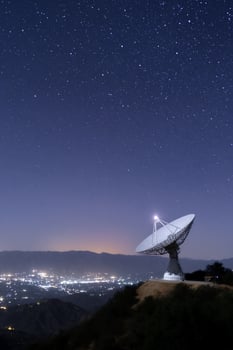 A large radio telescope stands illuminated against a backdrop of a starry sky photo