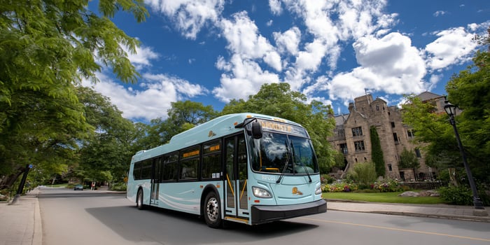 A light blue bus driving down the street photo