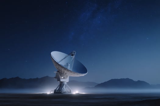 A satellite dish stands in a desert landscape, pointed at a starry night sky photo