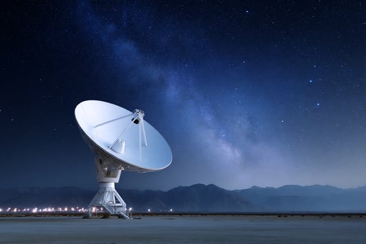 A radar dish points toward the milky way in the night sky. Mountains in distance photo