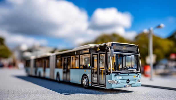 Articulated blue bus heads toward viewer on a road under a bright blue sky photo