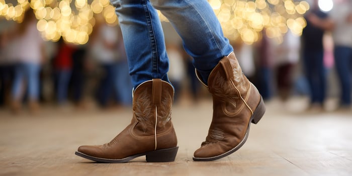Boots on the dance floor. People dance together with lights, blue jeans and boots photo