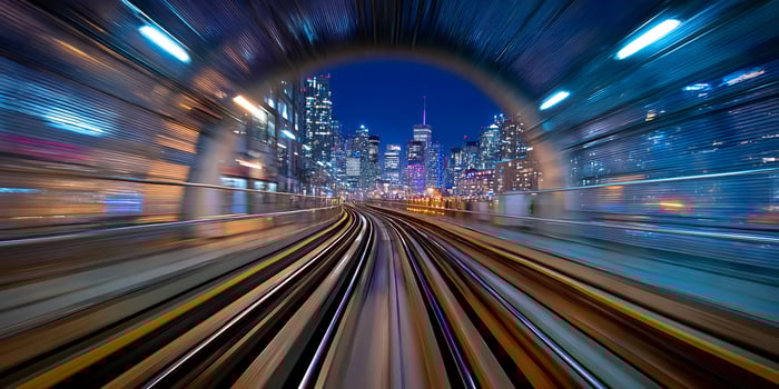 City lights shine through the tunnel opening as a train speeds through photo