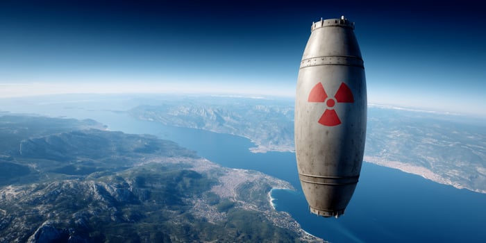 Metal bomb with the radiation symbol flying over the water and landscape below photo