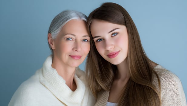 Older woman and young woman, headshot, posing on light blue backdrop in sweaters photo