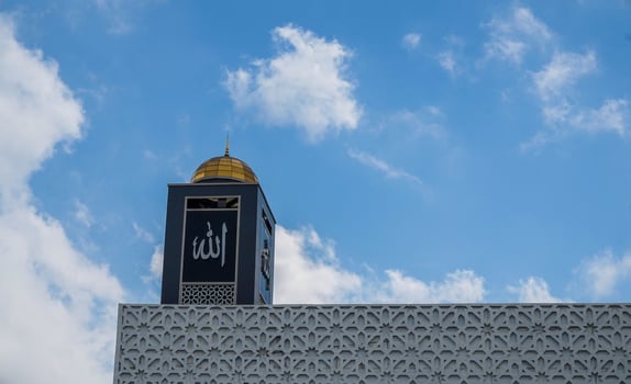 Minaret with Islamic Calligraphy Against Blue Sky with Clouds photo
