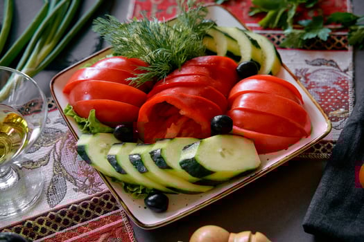 Freshly Sliced Cucumbers and Tomatoes Artistically Arranged on a Decorative Plate, Garnished with Olives and Herbs, Perfect for a Colorful Healthy Meal photo