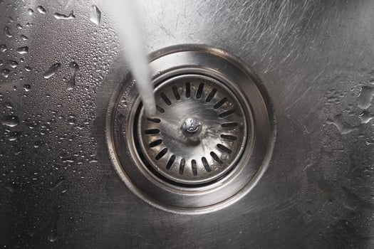 Water flowing into a stainless steel sink drain photo