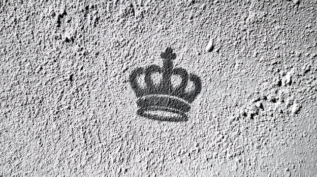 Shadow of a Royal Crown Stenciled on Textured Gray Wall. photo
