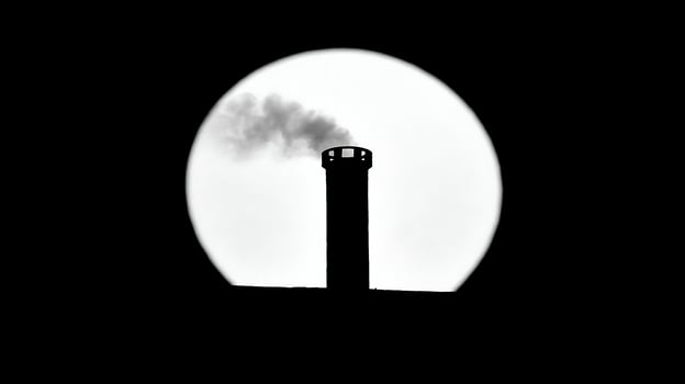 Silhouette of a smokestack against the moon. photo