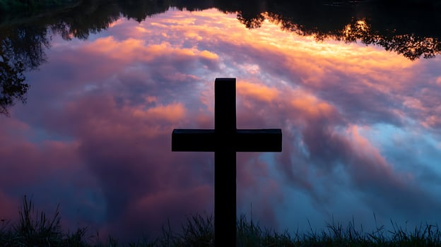 Cross Silhouette Against Dramatic Sunset Reflection on Water. photo