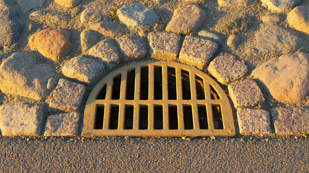 Sunlight Bathes Old Cobblestones and Drain Grate in Warm Golden Light. photo