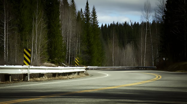 Winding Forest Road with Guardrail and Warning Sign. photo