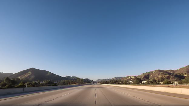 Open Highway Towards Distant Mountains Under a Clear Blue Sky. photo