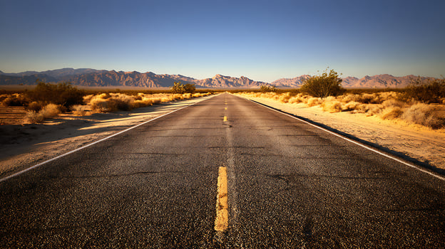 Endless Desert Highway Leading Towards Majestic Distant Mountains. photo