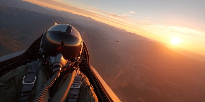 Pilot flying jet over mountain at sunset. Second plane visible in background photo