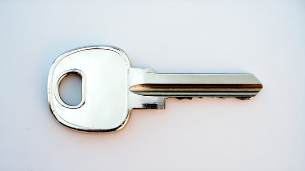 A single silver key with a textured metal edge on a white background. photo