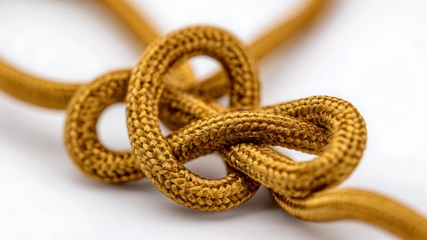 Detailed Close Up of a Tied Golden Rope Knot on a White Background. photo