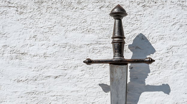An Ancient Sword Stands Strong Against a Textured White Wall. photo