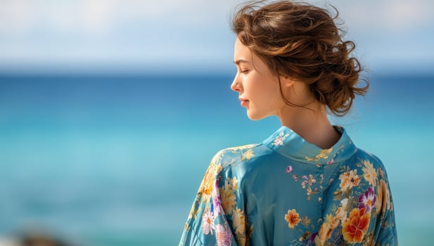 Young woman relaxing by the sea with floral kimono, enjoying the sun's warmth photo