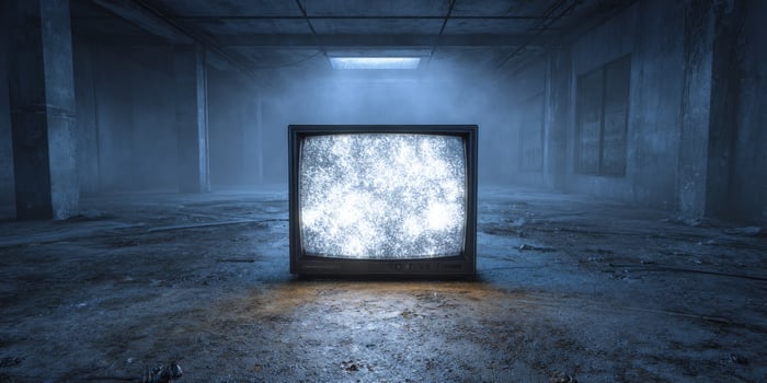 Abandoned TV with static in grungy, foggy room, symbolizing obsolete media use photo