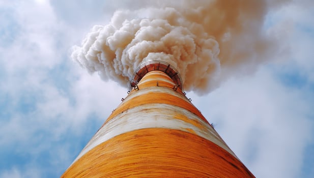 A Tall Chimney Emitting Pollution Against Cloudy Sky for environmental campaigns photo