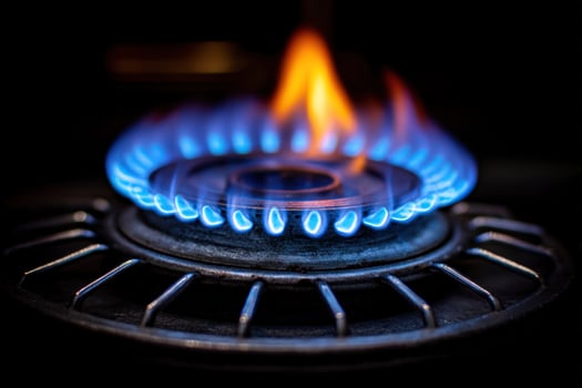A stovetop burner ignites, displaying blue and orange flames, encircled by a metallic grate photo