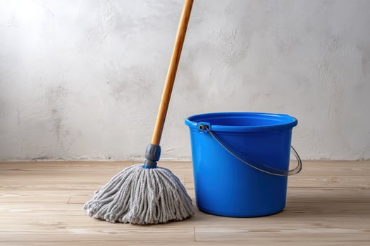 A blue bucket and mop lean against wall on floor photo